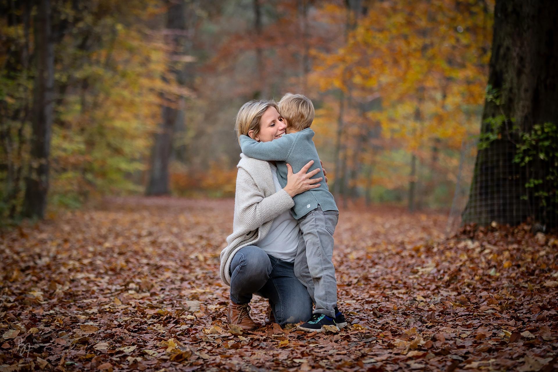 Familienfotografie München: Mutter mit Sohn beim Umarmen im Herbstlaub
