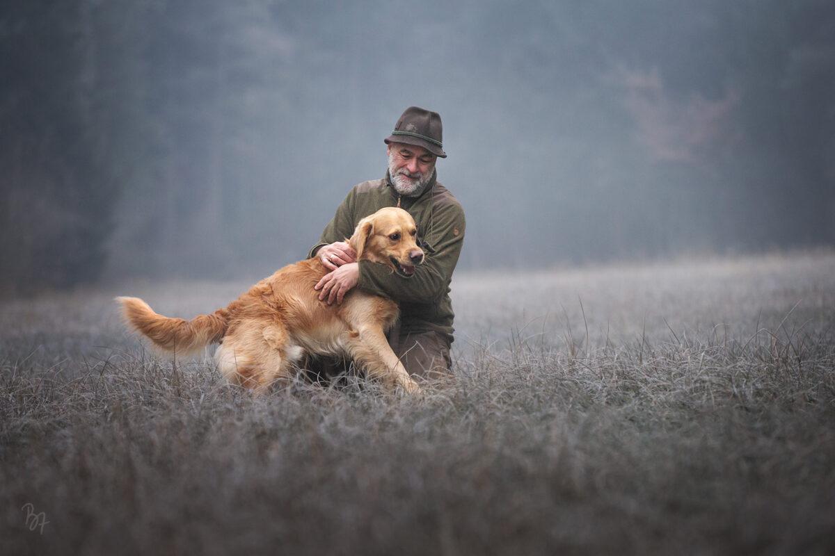 Foto eines Golden Retriever Hundes mit seinem Herrchen im winterlichen Wald