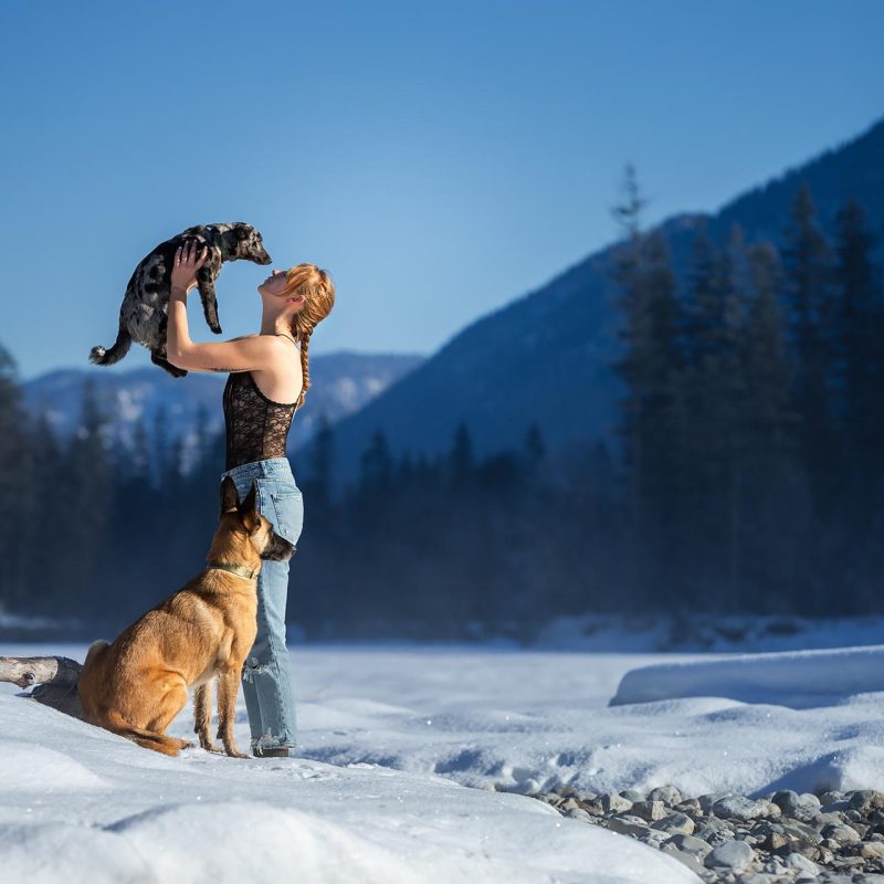 Frau mit zwei Hunden beim Fotoshooting in winterlicher Berglandschaft